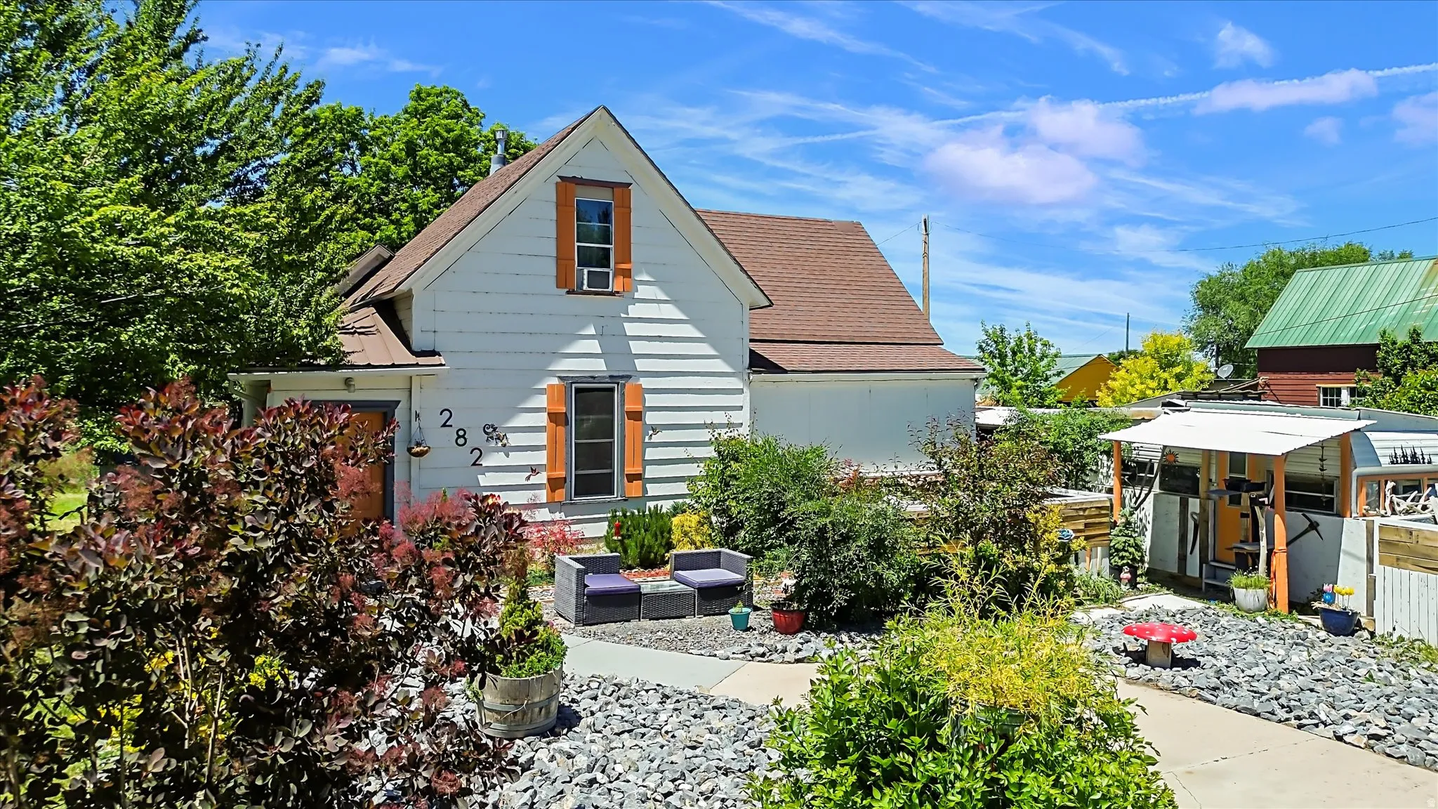 White siding exterior with a brown shingle roof, complemented by orange window shutters