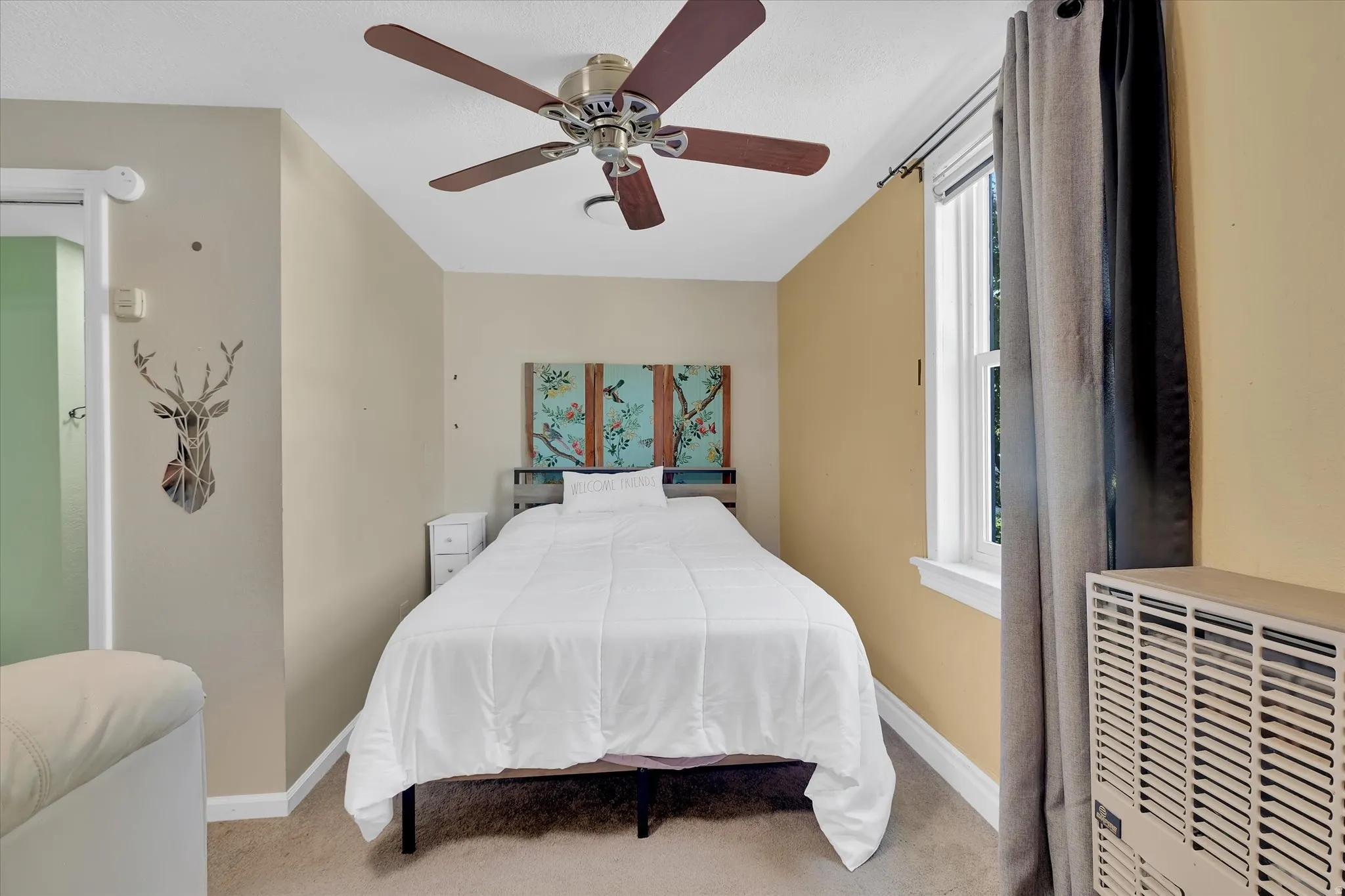 Carpeted room with a ceiling fan featuring wood-finish blades and a central light fixture