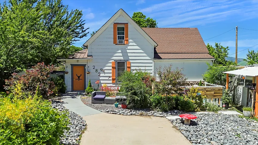 White siding residence featuring an orange front door, a side-gabled roof, and a gravel and concrete pathway
