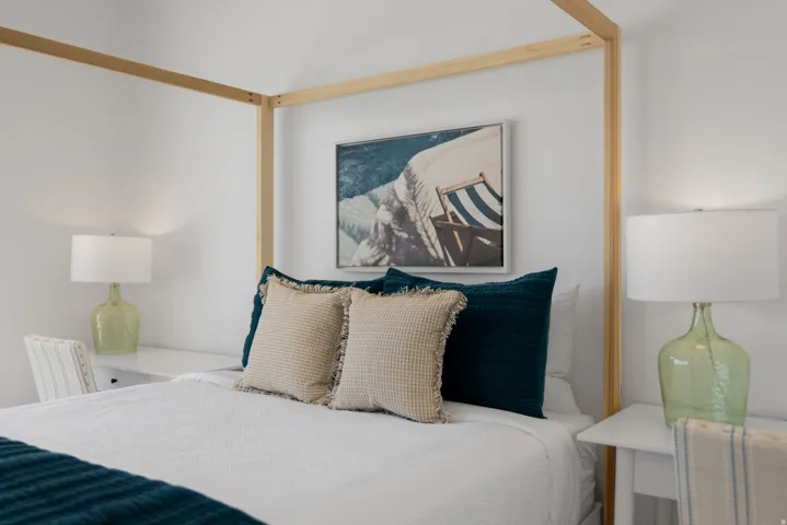 Bedroom featuring a light wood four-poster bed frame, white walls, and built-in white bedside tables