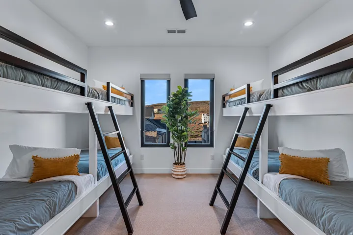 Built-in bunk beds with dark wood-finish frames and integrated ladders, recessed lighting, ceiling fan, and large windows with dark trim