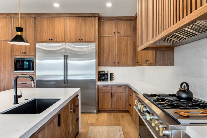 Gourmet kitchen with wood-finish cabinetry, white countertops, and integrated stainless steel appliances