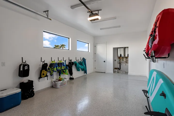 Spacious garage featuring a durable epoxy floor, multiple wall-mounted hooks, and two horizontal windows