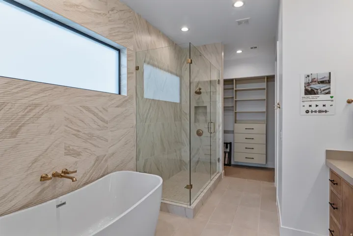 Modern bathroom with a freestanding tub, glass-enclosed shower, and built-in closet shelving