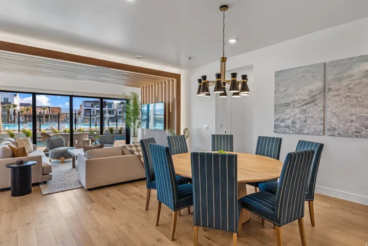 Open-concept living space featuring wood-finish flooring, a contemporary chandelier, and expansive windows