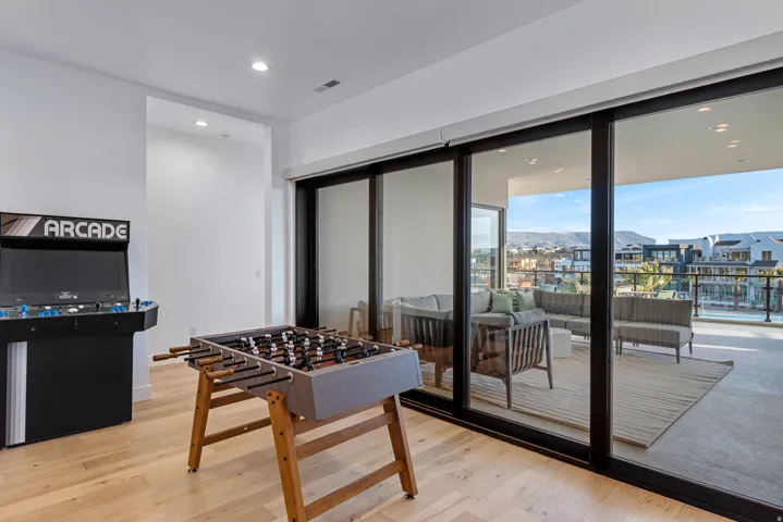 Expansive indoor-outdoor area featuring wide plank wood-finish flooring, recessed lighting, and a large sliding glass door system providing abundant natural light