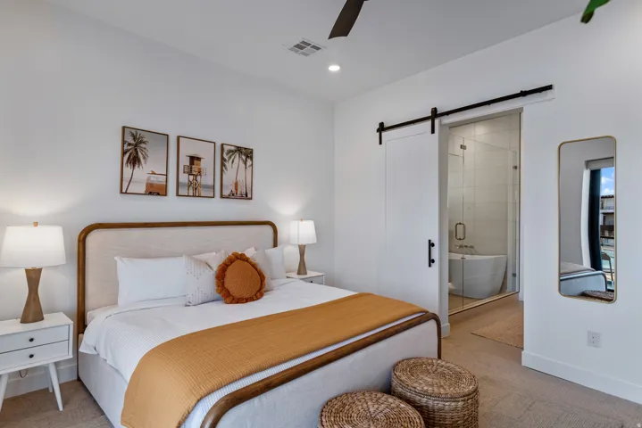 Bright bedroom featuring a white barn door entrance to a bathroom with a freestanding tub