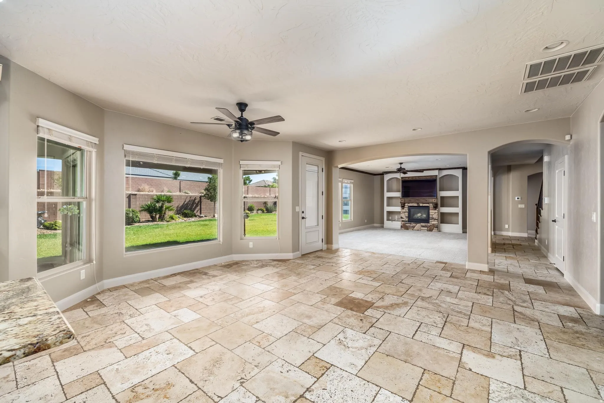 Expansive living area featuring varied-size stone tile flooring and a built-in media center with a stone-clad fireplace