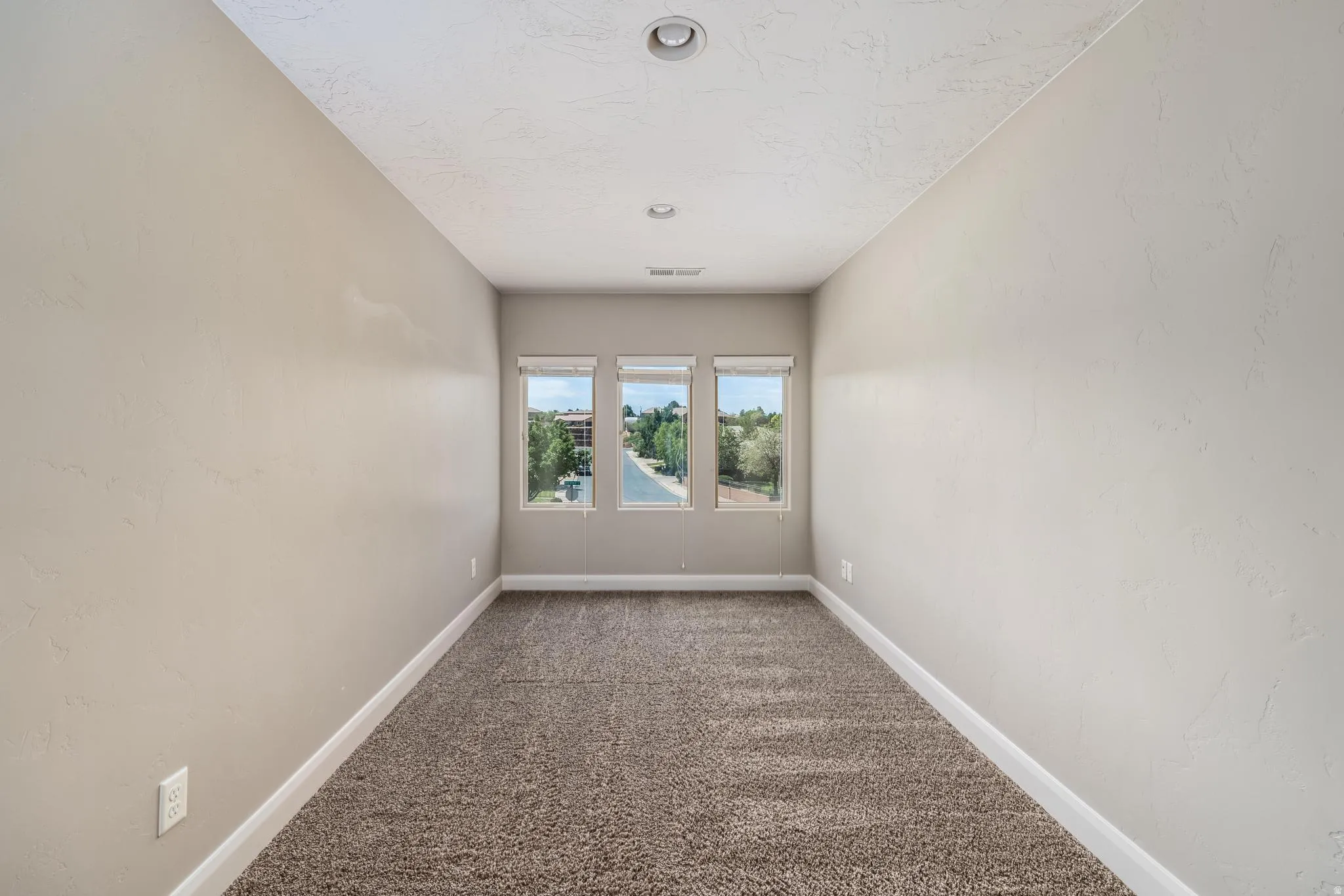 Carpeted room with three windows providing ample natural light