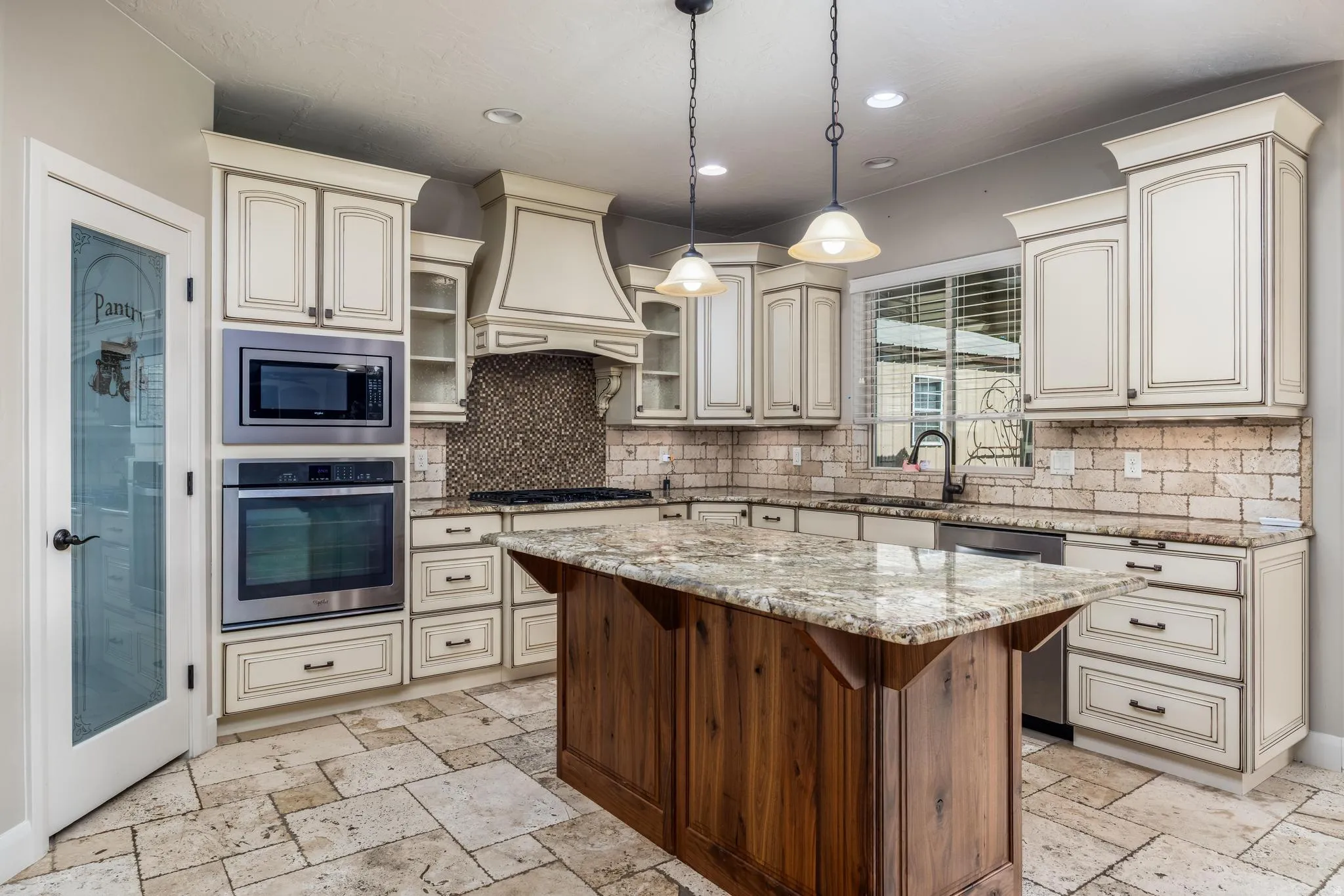 Kitchen featuring a large central island with a granite countertop, built-in stainless steel appliances, shaker-style cabinetry, and a subway tile backsplash