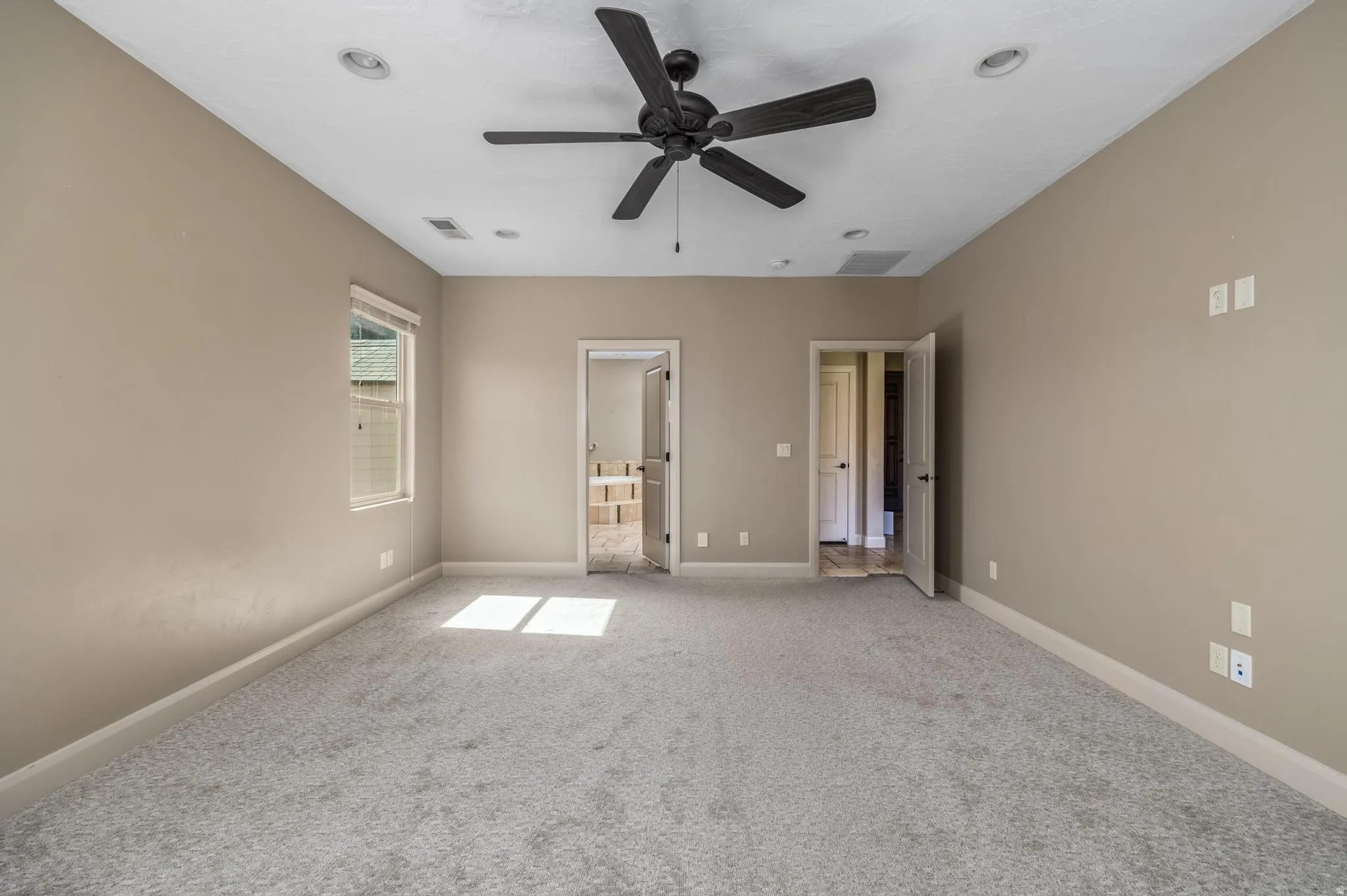 Spacious room featuring neutral carpeting, a ceiling fan, recessed lighting, and a window with blinds