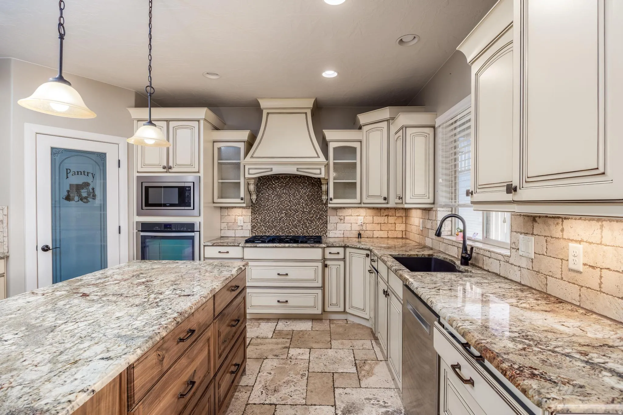 Gourmet kitchen featuring a large island with a stone countertop, custom cabinetry, built-in stainless steel appliances, and tile flooring