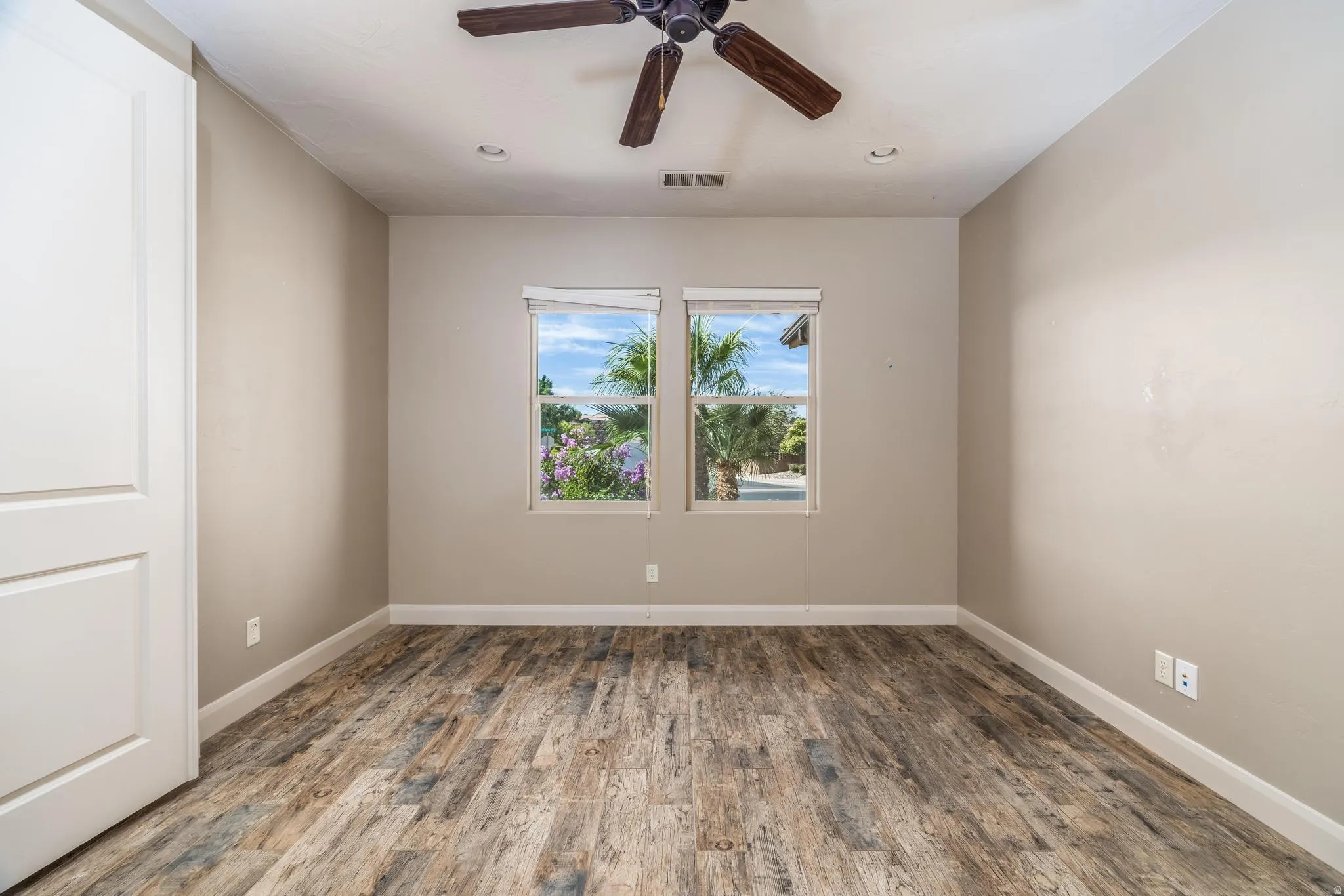 Room featuring wood-finish flooring, two large windows, a ceiling fan with light fixture, and recessed lighting