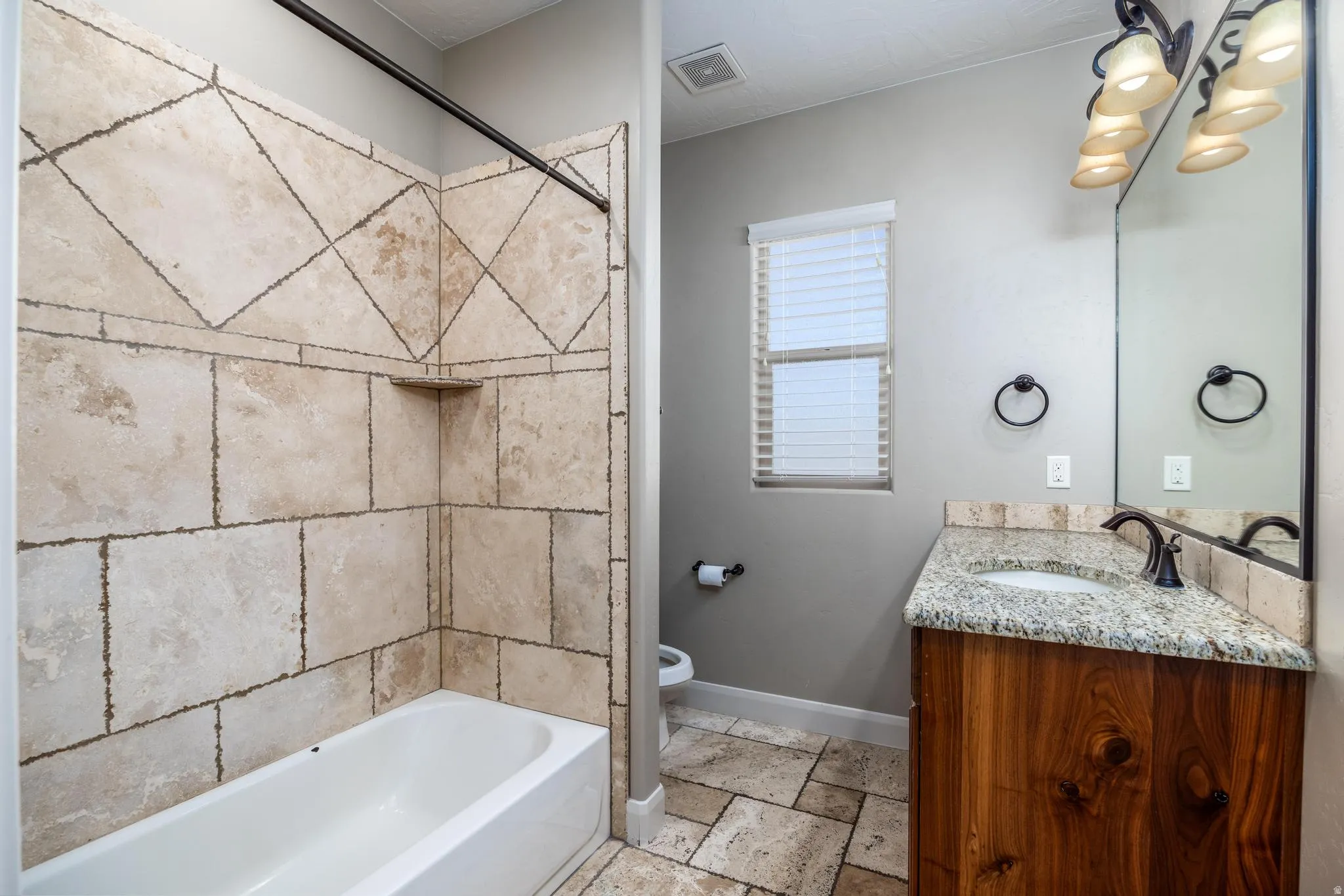 Bathroom featuring a wood-finish vanity with a granite countertop, undermount sink, and oil-rubbed bronze faucet
