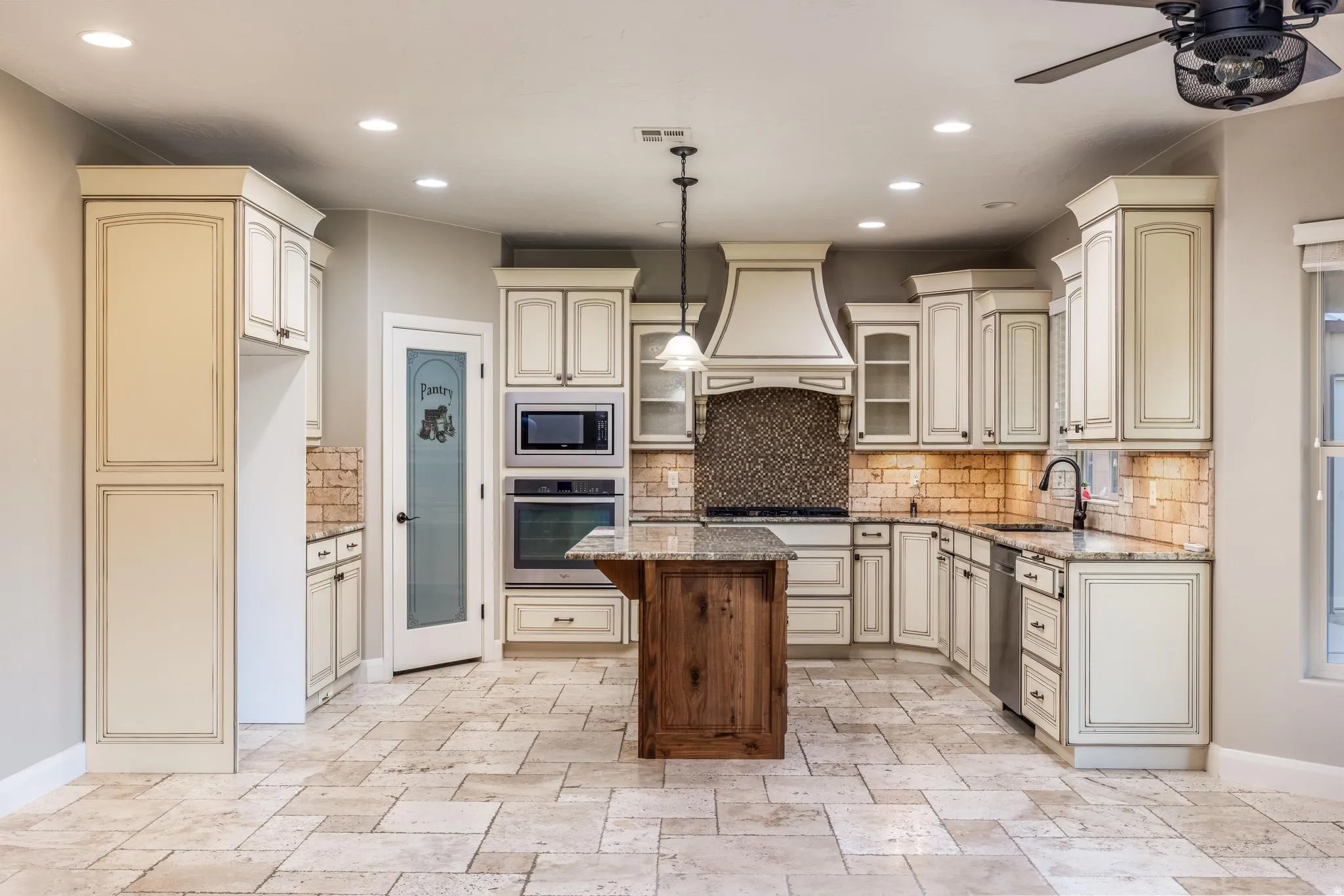Kitchen featuring light-toned cabinetry with dark accents, granite countertops, and a wood-finish island with a contrasting countertop