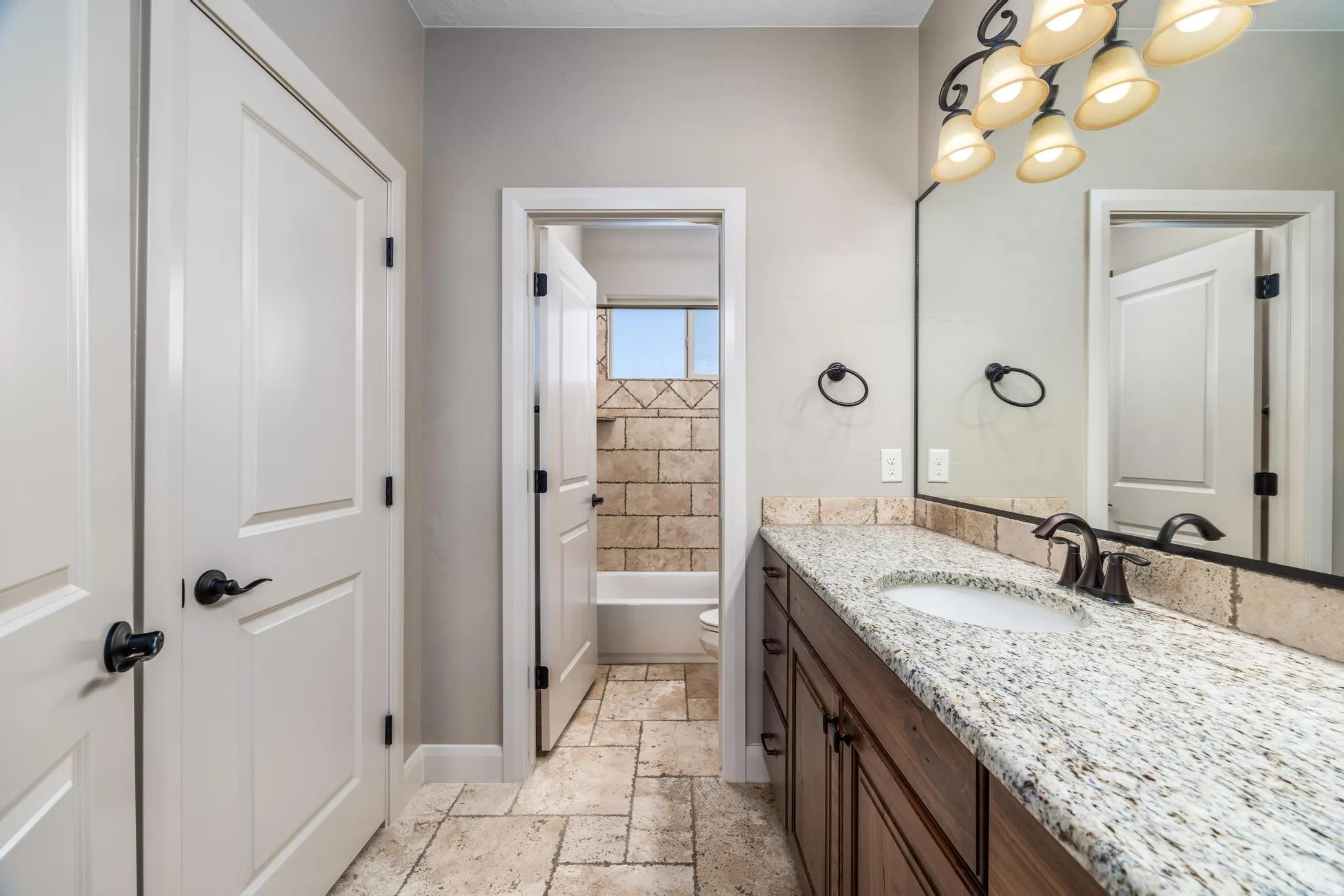 Bathroom vanity featuring a light granite-style countertop, integrated sink, and dark wood-finish cabinetry