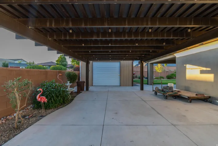 Spacious covered patio area featuring concrete flooring and a wood-beam ceiling