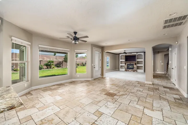 Expansive living area featuring varied-size stone tile flooring and a built-in media center with a stone-clad fireplace