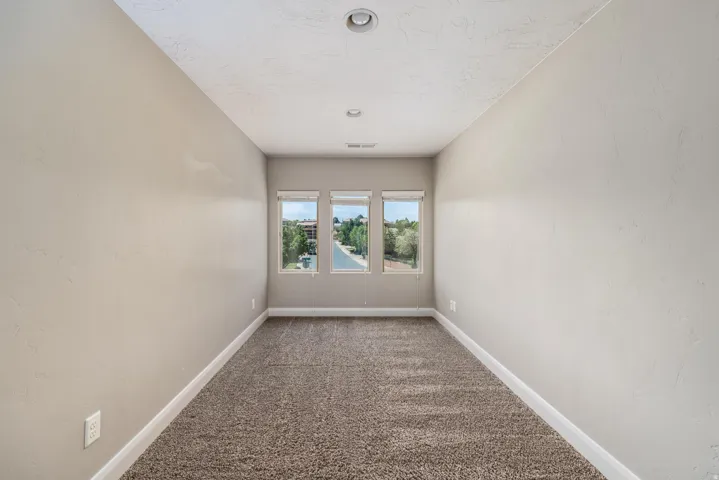 Carpeted room with three windows providing ample natural light