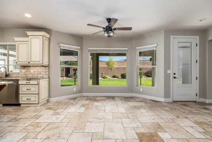 Open-concept living area featuring a kitchen with cream cabinetry, granite countertops, and a subway tile backsplash