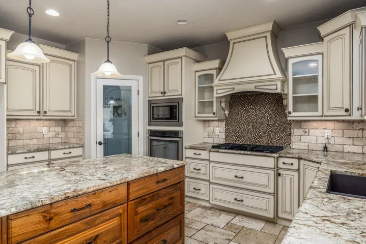 Gourmet kitchen featuring a central island with natural wood cabinetry and a stone countertop