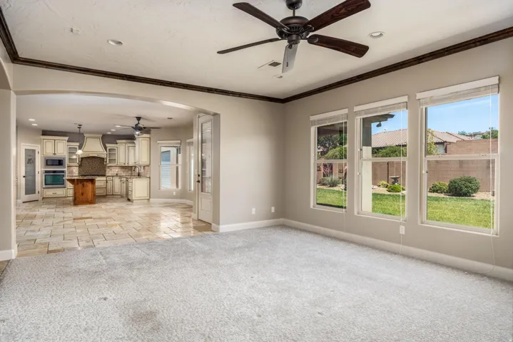 Spacious interior featuring three large windows, a ceiling fan, and crown molding