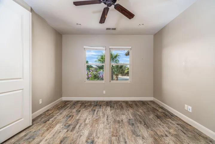 Room featuring wood-finish flooring, two large windows, a ceiling fan with light fixture, and recessed lighting