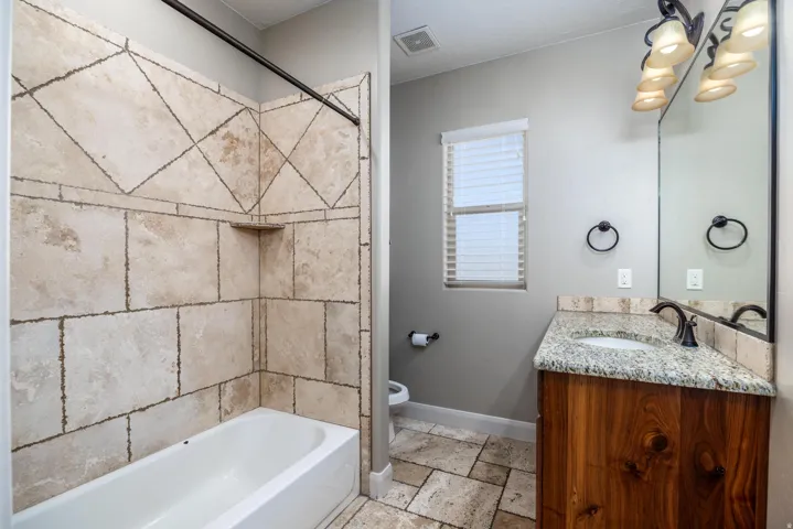 Bathroom featuring a wood-finish vanity with a granite countertop, undermount sink, and oil-rubbed bronze faucet