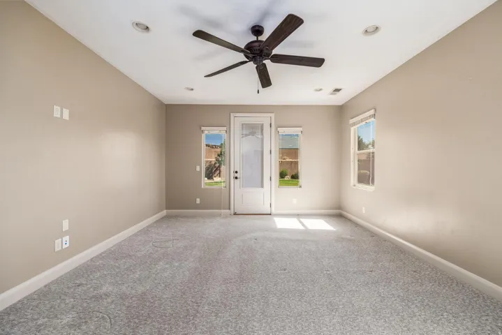 Spacious room featuring neutral wall paint, gray carpet flooring, a ceiling fan, recessed lighting, and a glass-paneled door with side windows