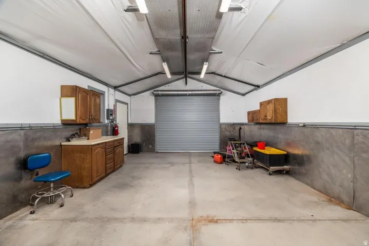 Spacious garage featuring a concrete floor, high vaulted ceiling, and a rolling garage door
