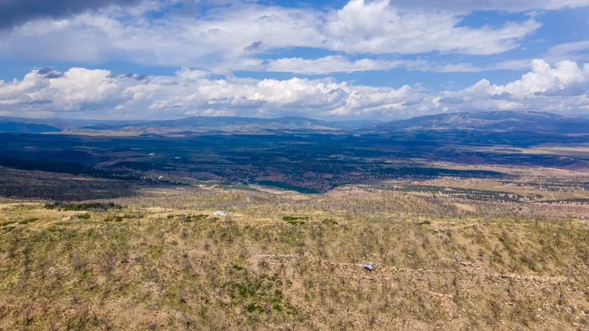 Expansive distant land with undulating terrain and mountain ranges under a partly cloudy sky