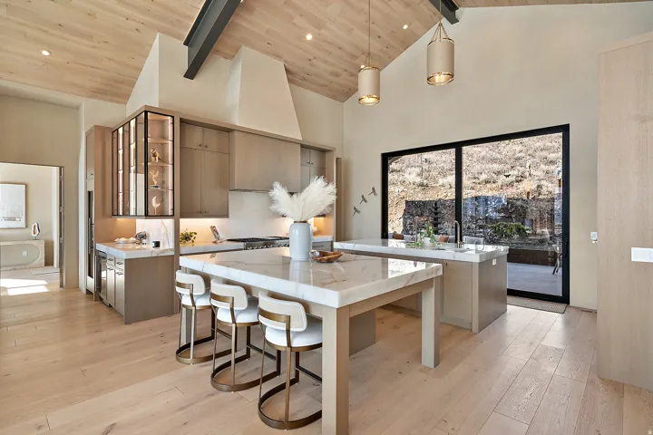 Expansive kitchen featuring a vaulted wood-finish ceiling, exposed structural beams, and light wood-finish flooring