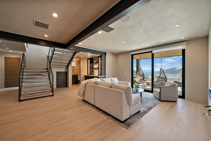 Spacious living area featuring light wood-finish flooring, recessed lighting, and exposed structural beams