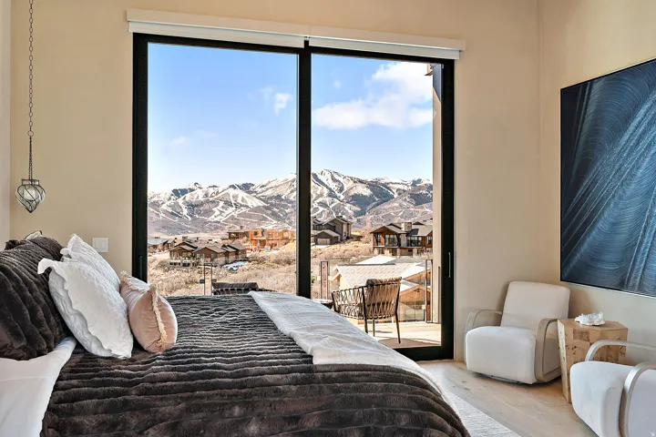 Room featuring floor-to-ceiling sliding glass doors, a mountain backdrop, a balcony, and light wood-finish flooring