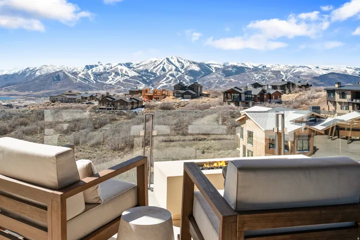 Outdoor living space featuring a glass railing, a built-in fire pit, and expansive mountain scenery