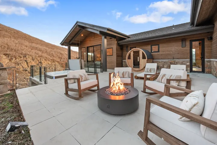 Expansive outdoor patio featuring a fire pit, hot tub, and barrel sauna