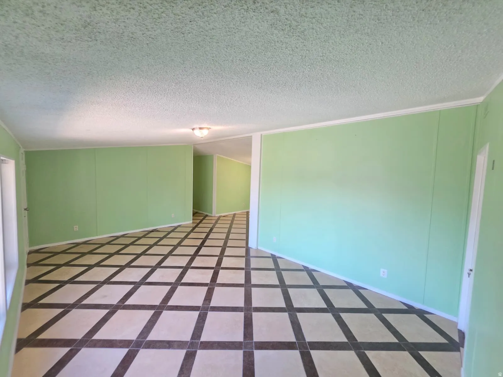 Spacious interior featuring patterned tile flooring, light green wall panels, and white trim