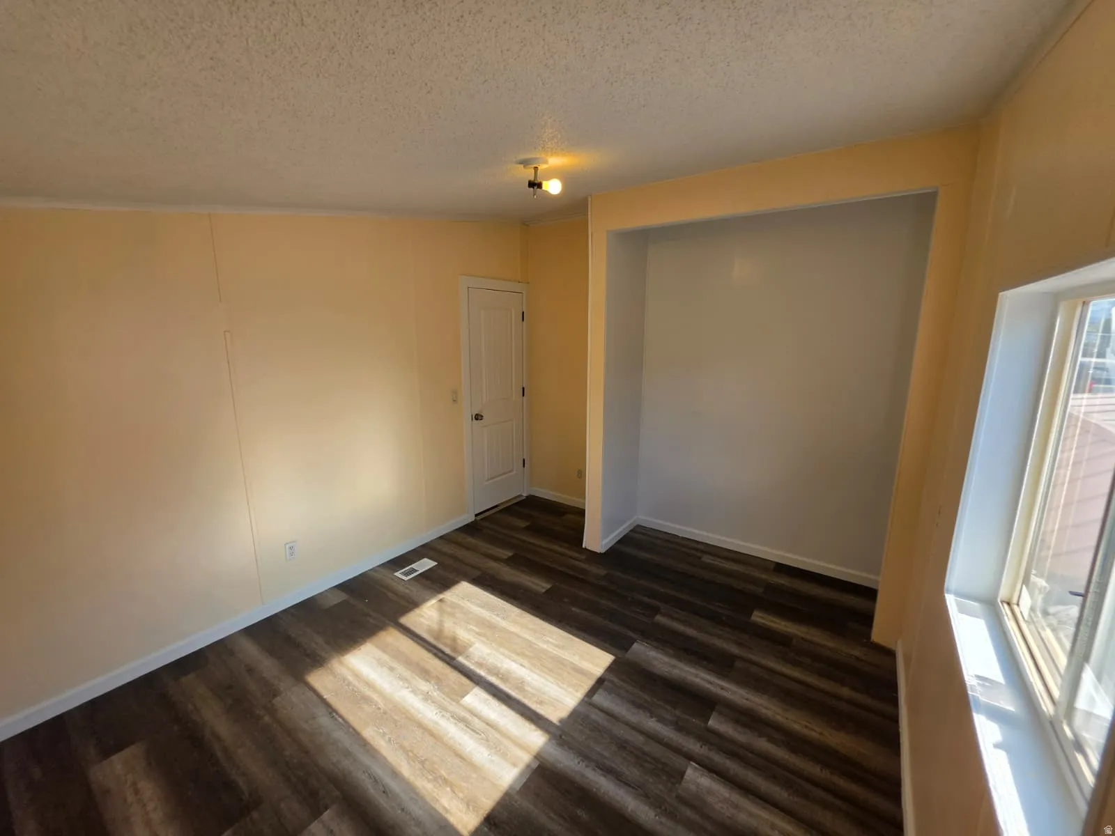 Room featuring wood-finish flooring, a built-in recessed niche, and a window with white trim
