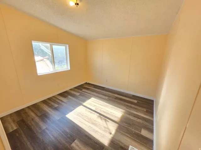 Room with wood-finish flooring, a window, and a ceiling-mounted light fixture