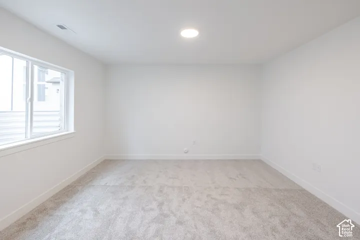 Neutral-toned interior space featuring wall-to-wall carpeting, crisp white wall finishes, and a single-pane sliding window
