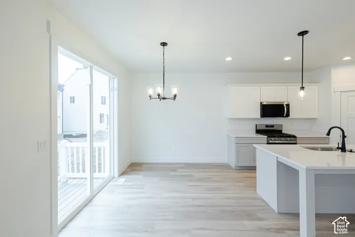 Open-concept area featuring wood-finish flooring, white cabinetry, quartz countertops, a kitchen island with a matte black faucet, and sliding glass doors