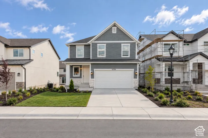 Two-story residence featuring a two-car garage, partial stone facade, and a covered porch entry