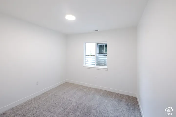 Neutral-toned wall-to-wall carpeting, crisp white walls, and a recessed ceiling light fixture, featuring a sliding window with a window sill