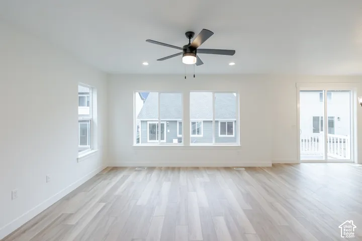 Wood-finish flooring, dual-pane windows, sliding glass door, recessed lighting, and matte black ceiling fan with integrated light fixture