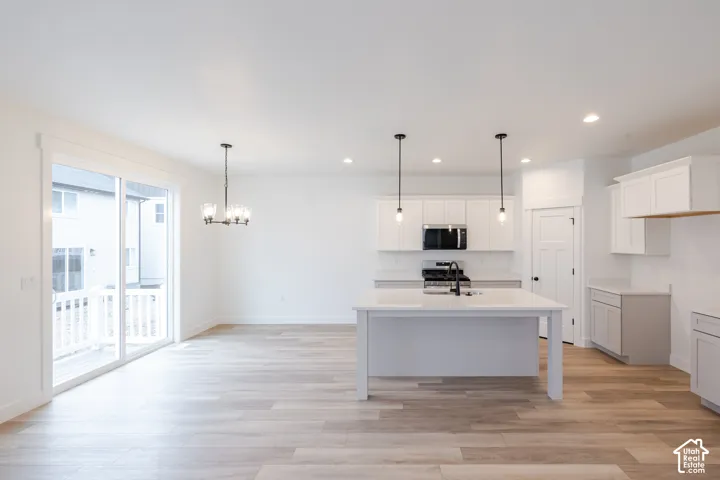 Kitchen featuring a central island with quartz countertops, wood-finish flooring, shaker-style cabinetry, recessed lighting, and sliding glass doors