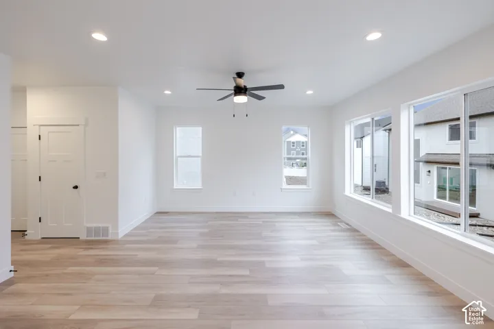 Neutral interior featuring wood-finish flooring, recessed lighting, a central ceiling fan, and large windows