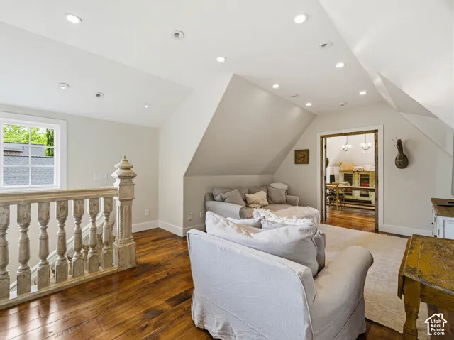 Spacious loft area featuring wood-finish flooring, recessed lighting, and a window providing natural light