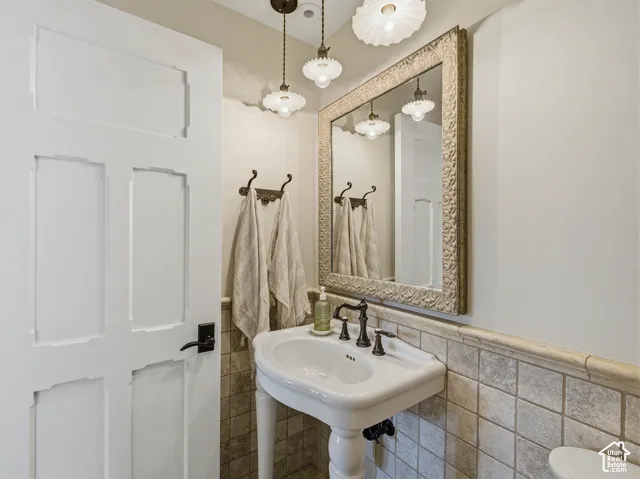 Pedestal sink with dark bronze faucet set, complemented by a framed mirror and two pendant light fixtures