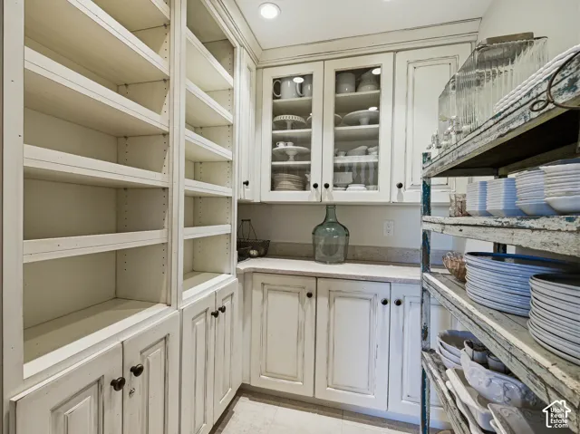 Integrated storage solutions featuring extensive built-in shelving, cabinet storage, glass-front upper cabinetry, and a light-toned countertop