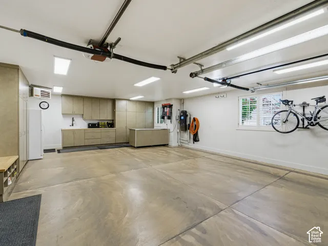 Spacious garage featuring extensive built-in cabinetry, an integrated sink with a countertop, recessed lighting, and a finished concrete floor